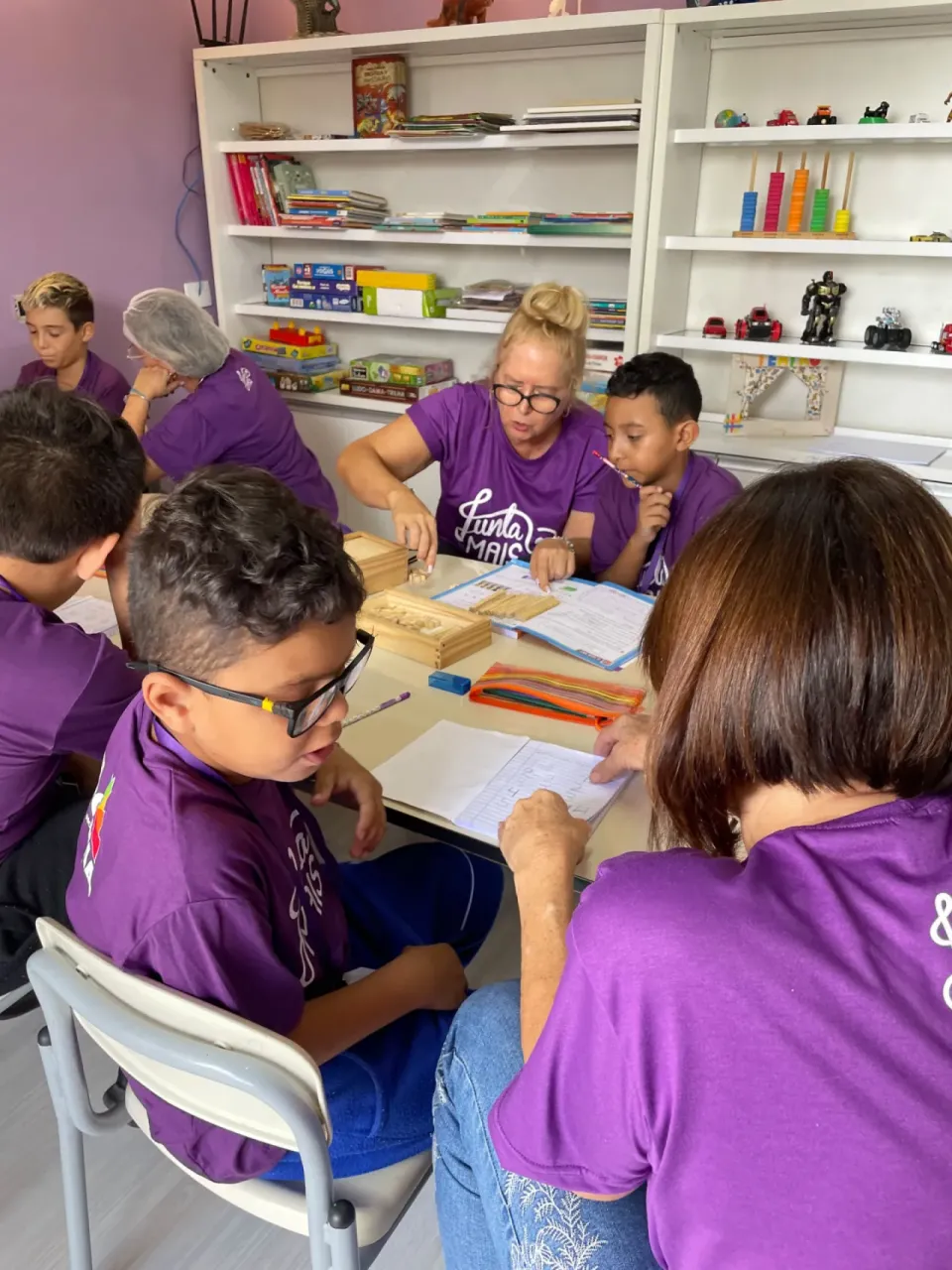 Educadoras e crianças da Junta Mais em atividade pedagógica com material didático, no contraturno em Curitiba